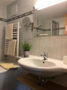 Baño blanco con lavabo y espejo en Gasthof Botenwirt, en Faistenau