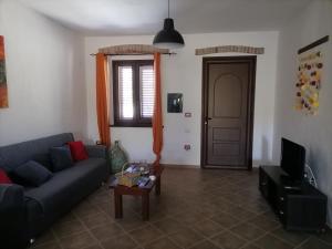 sala de estar con sofá, mesa y puerta en Casa di Stefano, en Villamassargia
