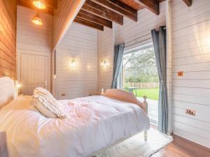 a bedroom with a bed and a large window at Little Yew Tree Lodge in Hambledon