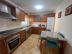 a kitchen with wooden cabinets and a table with chairs at Villa with private pool and beautiful garden in Los Cristianos