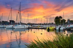 un groupe de bateaux amarrés dans un port de plaisance au coucher du soleil dans l'établissement Apartamenty Portowe, à Mikołajki