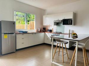 a kitchen with white appliances and a table with chairs at Ana iti Lodge PAEA Tahiti in Paea