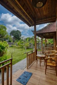 a porch with chairs and a table and a view of a field at Tegal Besung Cottage in Nusa Penida