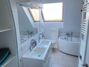 a white bathroom with two sinks and a bath tub at Penthousewohnung Küstenzauber 22 in Großenbrode