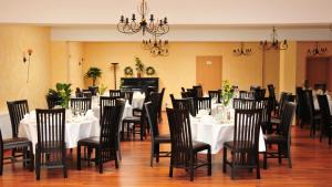 a dining room with white tables and black chairs at Landhaus Hammoor Stieper Gastronomie GmbH in Hammoor