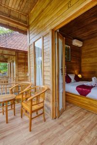 a bedroom with a bed and two chairs on a porch at Tegal Besung Cottage in Nusa Penida