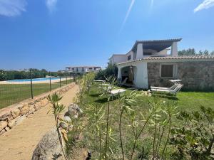una casa con una valla al lado de un patio en House 40 in Capannizza Pool Complex next the beach, en Budoni