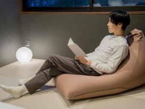 un hombre sentado en una silla de bolsa de frijoles leyendo un libro en Rakuten STAY VILLA Yatsugatake - 101 Stylish Design - en Hokuto