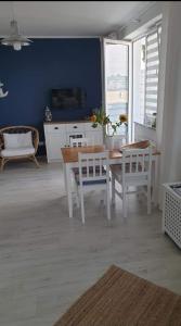 een eetkamer met een tafel en stoelen en een blauwe muur bij Apartamenty Trio in Dziwnówek