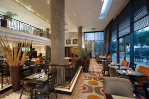 um restaurante com mesas e cadeiras e janelas grandes em The RidgePoint Hotel em Witbank