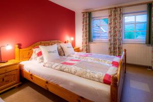 Schlafzimmer mit einem Holzbett mit roten Wänden in der Unterkunft Ferienwohnungen Hotel Garni Dörflerwirt in Aflenz Kurort