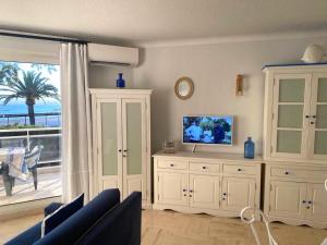 ein Wohnzimmer mit einem TV und einem großen Fenster in der Unterkunft Appartement sur la Plage, Le Royal Beach in Saint-Laurent-du-Var