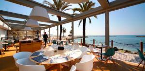 a restaurant with white chairs and tables and the ocean at Appartement sur la Plage, Le Royal Beach in Saint-Laurent-du-Var