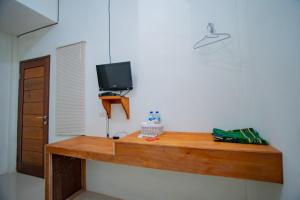 een houten bureau met een televisie aan de muur bij RedDoorz Syariah near Rembele Airport Bener Meriah in Tingkeum