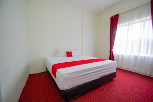 1 dormitorio con cama blanca y alfombra roja en RedDoorz Syariah near Rembele Airport Bener Meriah, en Tingkeum