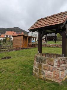 a wooden pavilion in a field next to a building at Ferienwohnung Madenburgblick in Eschbach