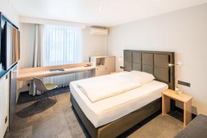 a bedroom with a bed and a desk in it at Hotel Cult Frankfurt City in Frankfurt