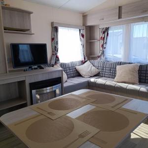 a living room with a couch and a tv at Caravan Aan Zee Arnani in Middelkerke