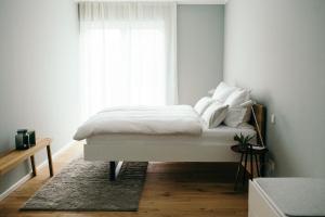 una camera da letto con un letto con lenzuola bianche e una finestra di Moselhaus by Clüsserath-Wittmann a Trittenheim