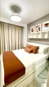 ein Schlafzimmer mit einem großen weißen Bett mit braunen Kissen in der Unterkunft Condo directo a la piscina en Hard Rock Punta Cana area in Punta Cana
