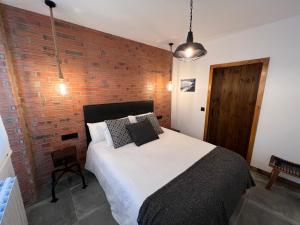 ein Schlafzimmer mit einem Bett und einer Ziegelwand in der Unterkunft Alojamientos Rías Baixas - Mares del Forte- Cangas in Cangas