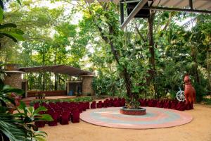 Advaitha Serenity Resorts في Kālvādi: المسرح والكراسي الحمراء والشجر في الوسط