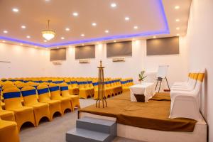 a lecture hall with yellow chairs and a stage at Advaitha Serenity Resorts in Kālvādi