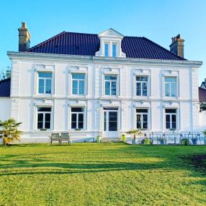 une grande maison blanche avec une grande cour dans l'établissement La Carte Postale, à Oye-Plage