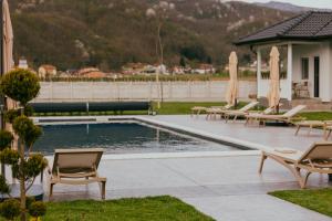 a swimming pool with chairs and umbrellas at Apartmani Darijana in Ljubovija