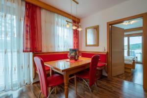 a dining room with a wooden table and red chairs at enJoy Appartements in Sankt Kanzian