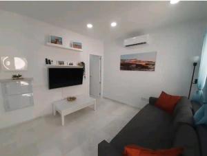 a living room with a couch and a flat screen tv at Casa Playa Caleta, a 4 minutos de la playa in Cádiz
