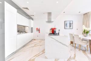cocina con paredes blancas y mesa con sillas en Lavish & Equipped oceanfront 2 BR facing Ain Dubai, en Dubái