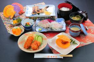 una mesa cubierta con platos de comida y palillos chinos en Tennenonsen Amuri en Amakusa