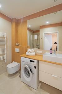 y baño con lavadora y lavamanos. en Apartament DUNE SurfingBird Dźwirzyno, en Dźwirzyno