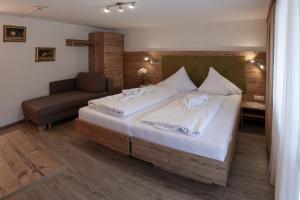 a bedroom with a large bed and a chair at Hotel Neuwirt in Mieming