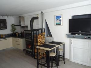 a kitchen with a table and stools and a tv at Maison entre Loire et châteaux in Menars