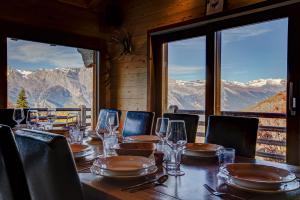 a table with chairs and wine glasses and a view of mountains at Chalet le Cerf in La Tzoumaz