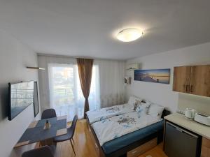 a small room with a bed and a table at Апартамент за гости Магнолия Резиденс in Sunny Beach