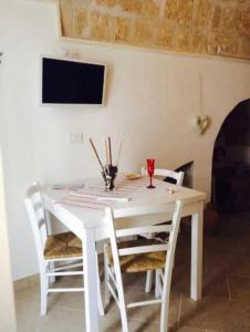 a white dining room table with white chairs and a tv at Petali Rosa Dimora Rossa in Polignano a Mare