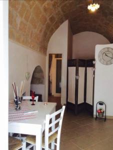 a dining room with a table and a clock on the wall at Petali Rosa Dimora Rossa in Polignano a Mare