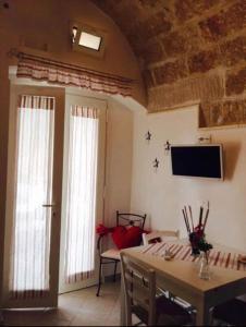 a living room with a table and a tv on the wall at Petali Rosa Dimora Rossa in Polignano a Mare