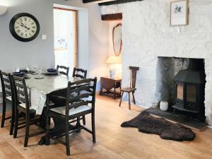 a dining room with a table and a fireplace at Annies Cottage in Edinbain