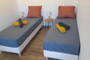 two twin beds in a room with a table at Appartement lumineux et central in Propriano