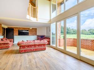Freds Barn في Swanton Abbot: غرفة معيشة بأثاث احمر ونوافذ كبيرة