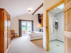 a bathroom with a shower and a bed in a room at Freds Barn in Swanton Abbot
