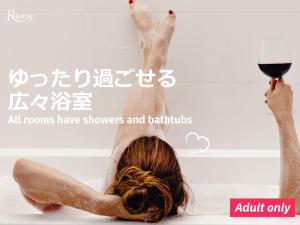 a woman laying in a bath with a glass of wine at Restay Tokushima Aine (Adult Only) in Tokushima