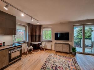 a kitchen with a living room with a table and a tv at Apartament VIP PROMENADA in Mrągowo