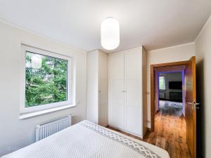 1 dormitorio con cama blanca y ventana en Apartament VIP PROMENADA, en Mrągowo