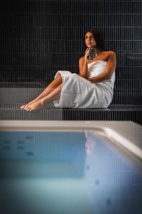 una donna seduta su un letto accanto alla piscina di Hotel Posillipo a Gabicce Mare