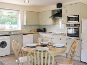 a kitchen with a wooden table and chairs and a kitchen with white cabinets at Riverside Cottage in Boreland